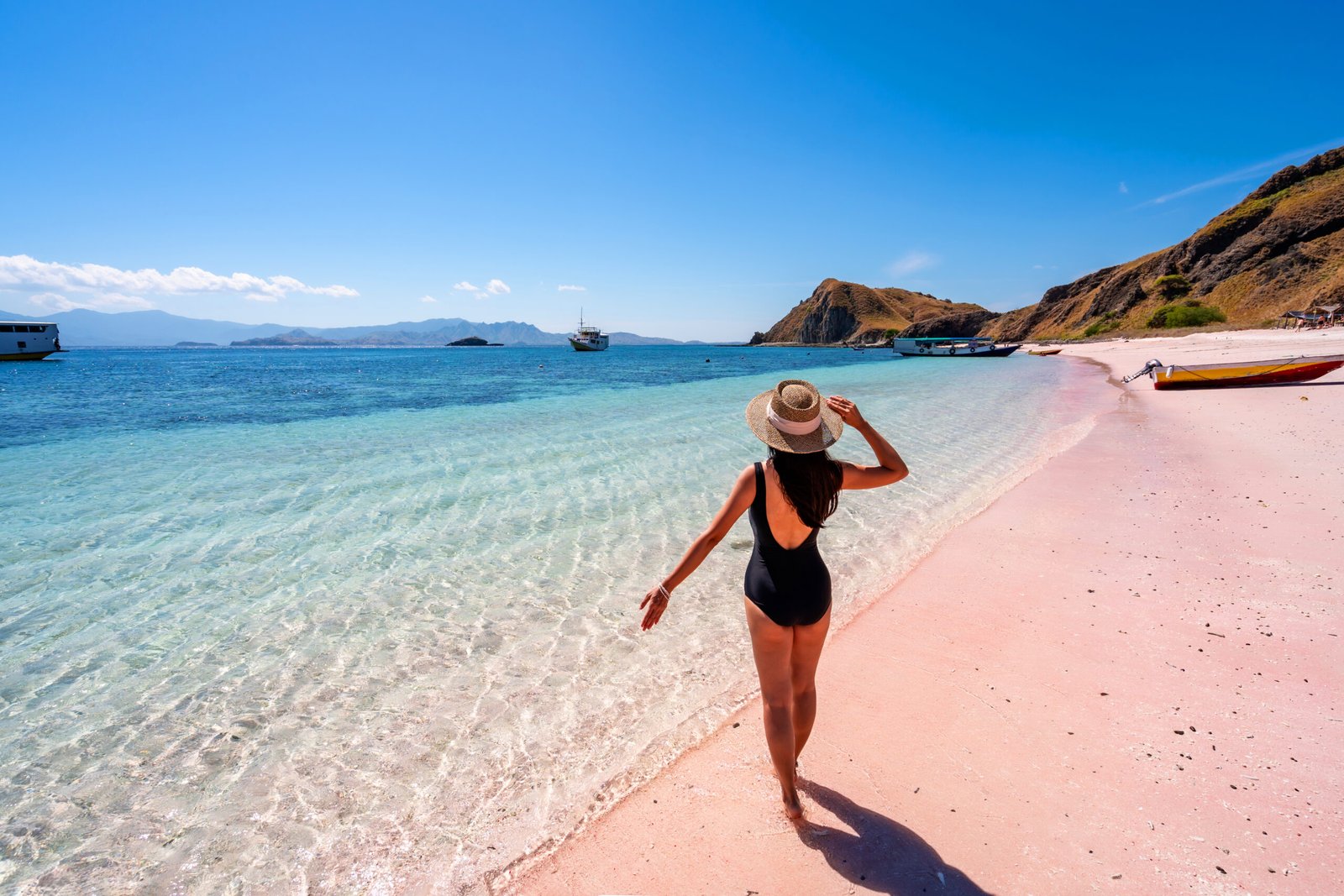 Young female tourism enjoying the tropical pink sandy beach with clear turquoise water at Komodo islands in Indonesia
